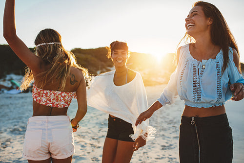 Three young female friends dancing on the sea shore