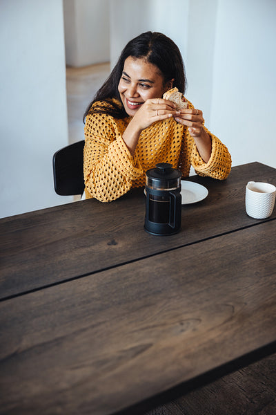 Smiling woman enjoying a lunch break at work with coffee