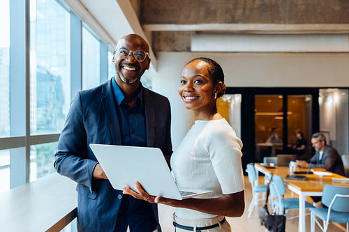 Smiling coworkers with a laptop in a bright, professional office setting