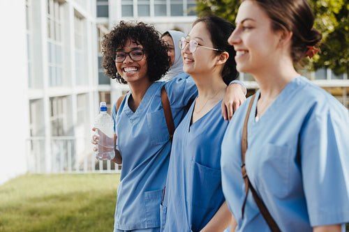 Diverse, happy female students coming from class in medical scrubs