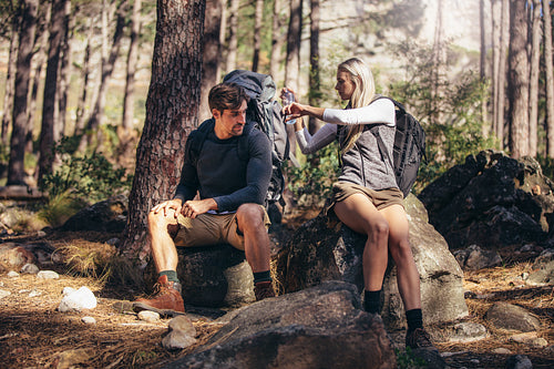 Hiking couple relaxing sitting on rocks during trekking