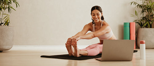 Woman doing yoga watching video on laptop