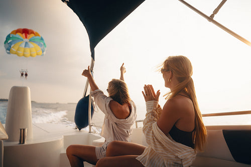 Cheering friends on a boat enjoying a parasailing adventure during holiday