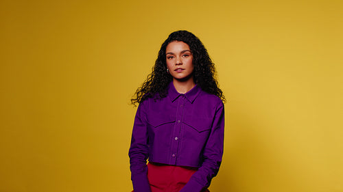 Portrait of a young woman posing on a yellow background