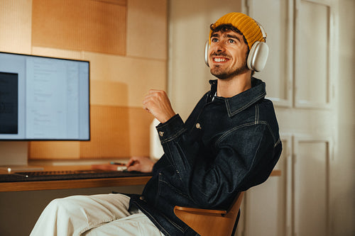 Happy man smiles while working with headphones at a computer desk