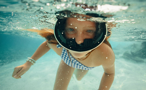Young girl swimming underwater with a mask in a tropical destination