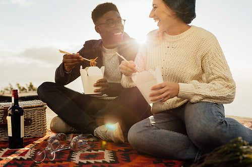 Interracial couple on picnic enjoying having food