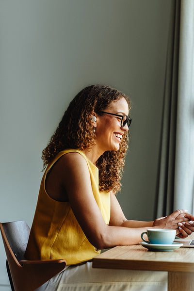 African woman at desk joins remote video call with coffee at home