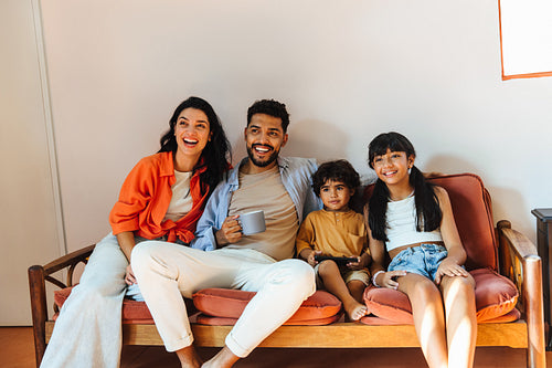 Happy Latino family relaxing together on a cozy sofa in bright interior.