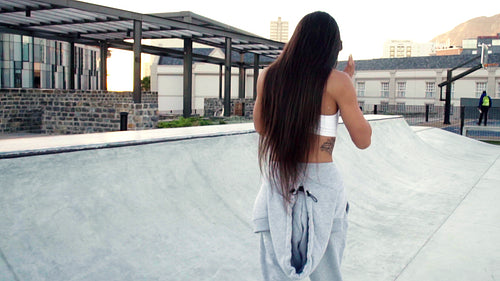 Happy female skater walking across a skate park