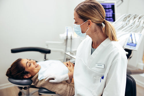 Dentist talking with female patient in clinic