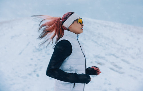 Mountain running leads the woman along a cold snowy trail during winter training