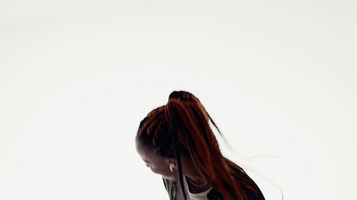 Young black woman dancing joyfully to music with earbuds and smartphone in studio