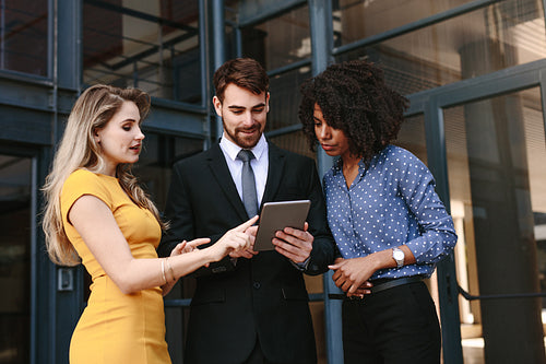 Corporate professionals discussing work using digital tablet
