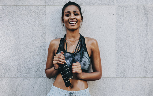 Fitness woman standing outdoors holding a skipping rope on her neck