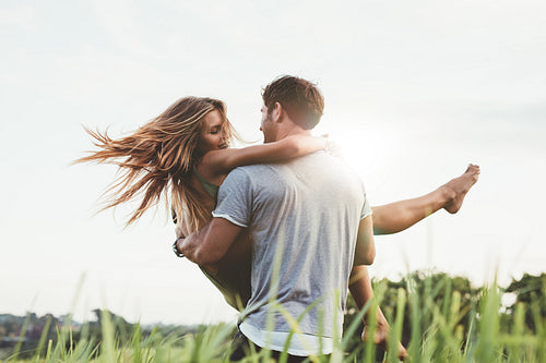 Man carrying girlfriend in  grass field