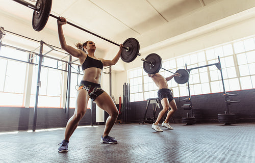  Man and woman doing weightlifting exercises in gym