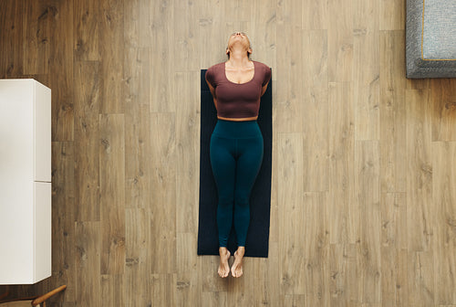 Overhead view of a woman practicing a yoga pose on a fitness mat