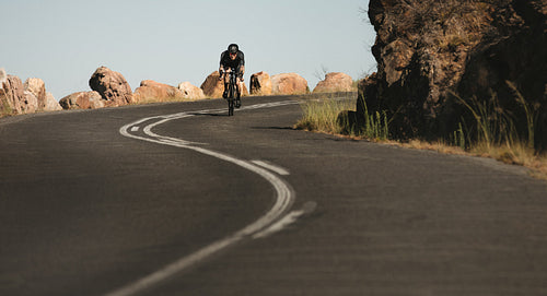 Cyclist coming down hill on mountain road
