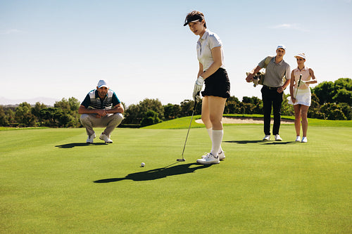 Focused golfers on a putting green showcasing team spirit and concentration