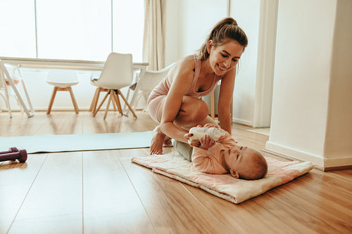 Yogi mother feeding her baby formula milk at home