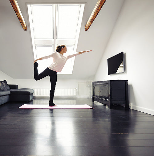 Beautiful woman practicing yoga exercises at home