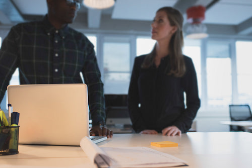 Table in office with business people standing by discussing