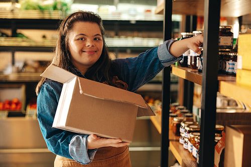 Convenience store employee with Down syndrome restocking food products