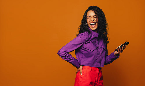 Vibrant orange background: Cheerful woman using smartphone for social media messaging