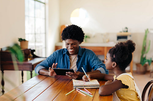 Happy Brazilian siblings using a tablet for learning and creative activties at home