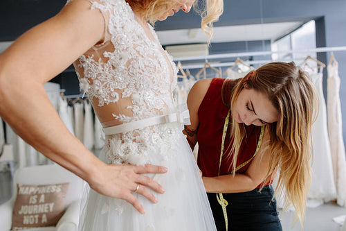 Skillful designer fitting bridal gown to bride