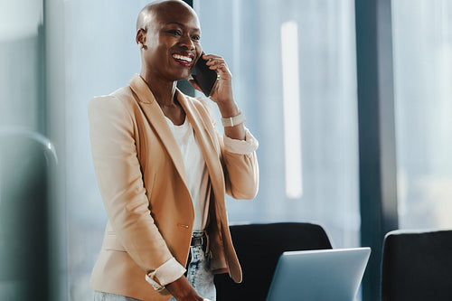 Businesswoman having a phone call and discussing work with a smile in the office