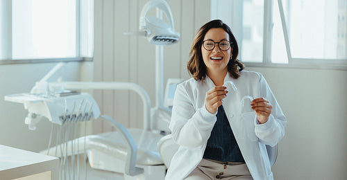 Dentist woman holding clear aligner in a modern dental clinic portrait