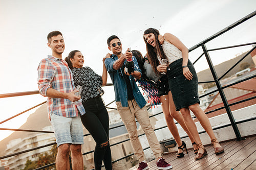 Young people celebrating with champagne at party on rooftop