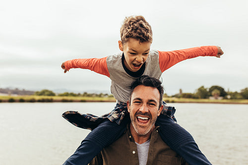 Father and son playing outdoors near a lake