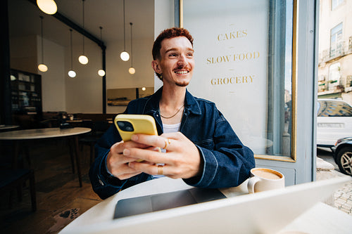Smiling man in cafe with coffee using smartphone