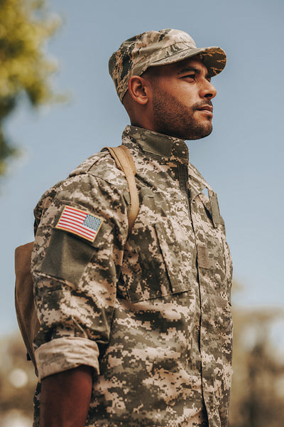 Patriotic young soldier standing at attention outside his home