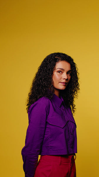 Young woman smiles and touches her hands together on a yellow background