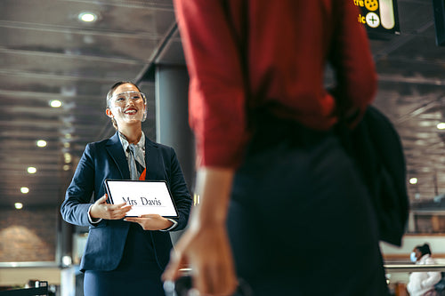 Chauffeur with a sign welcoming traveler on arrival gate
