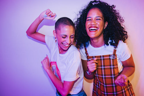 Two female friends dancing together at a house party