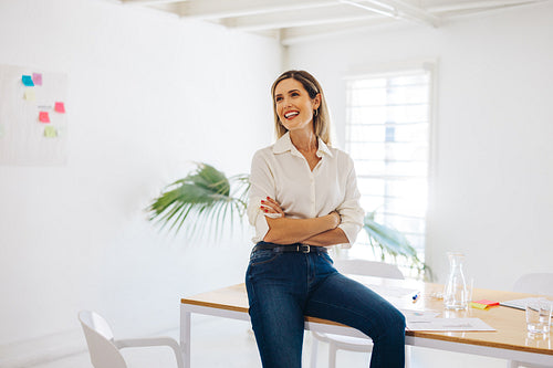 Successful businesswoman sitting on a conference table in an off