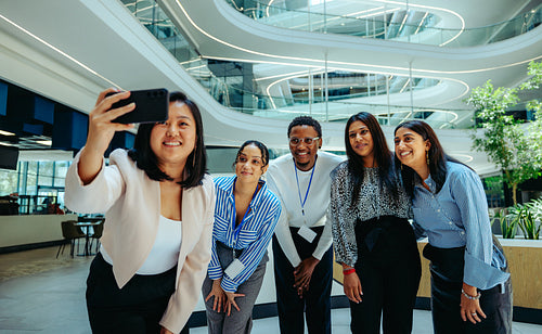 Stylish corporate accountants taking a group selfie in a contemporary workspace