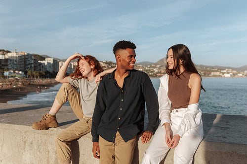 Group of young friends relaxing on a wall by the seaside