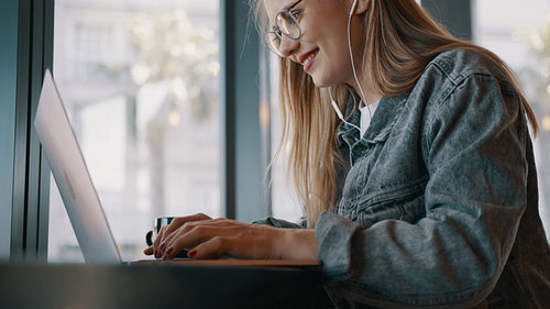 Smiling woman busy working on laptop at a cafe