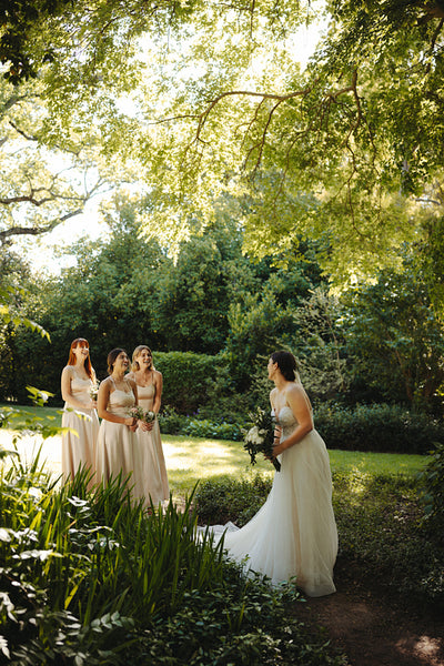 Bride and bridesmaids in a lush garden on a sunny wedding day