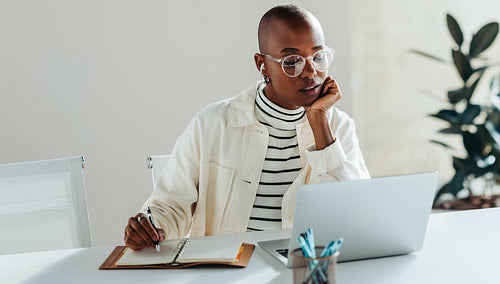 Professional woman working on laptop in modern office, displaying focus and productivity