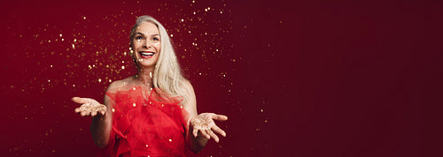 Excited senior woman throwing glitters