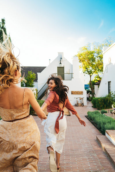 Excited woman leading her friend by the hand outdoors