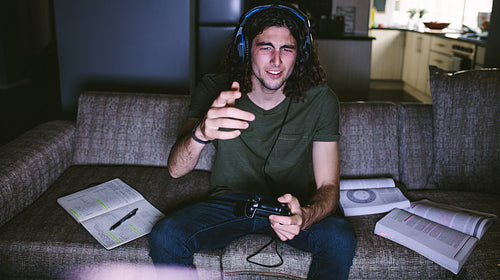 Student playing video game sitting at home