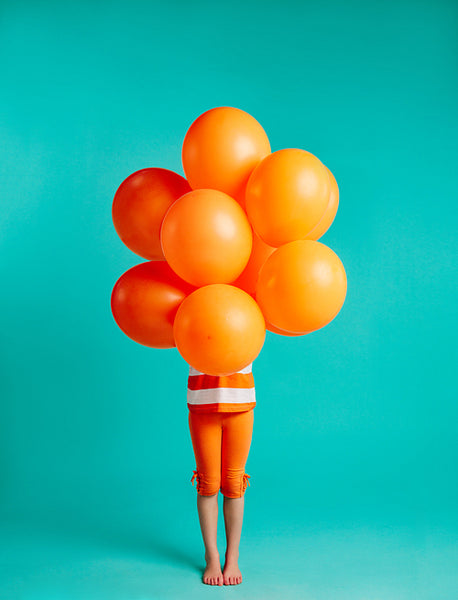 Girl holding orange balloons in front 